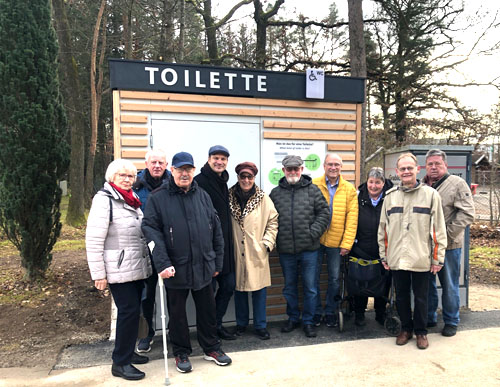 Menschen, die vor dem neuen Toiletten-Container, der mit Holz verkleidet ist, stehen.
